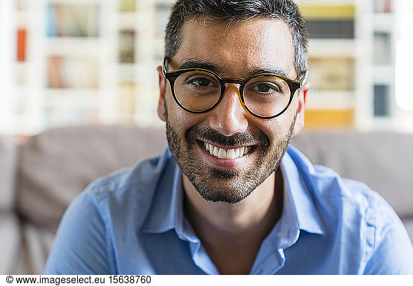 Portrait of happy young man wearing glasses at home