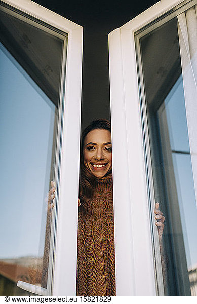 Portrait of happy young woman at the window