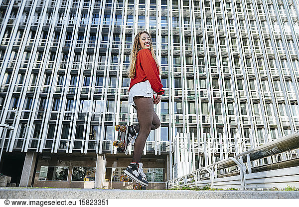 Portrait of happy young woman balancing on roller skates in the city