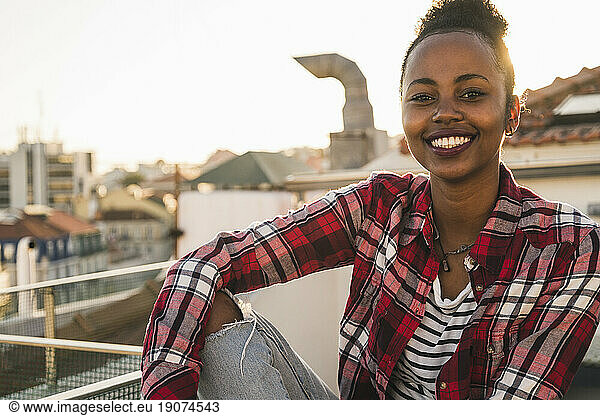 Portrait of happy young woman on rooftop at sunset