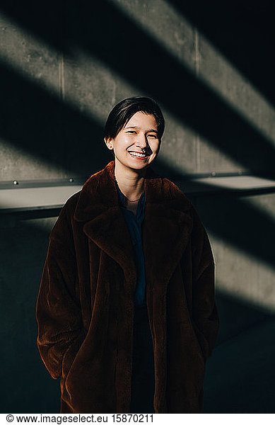 Portrait of happy young woman standing against wall