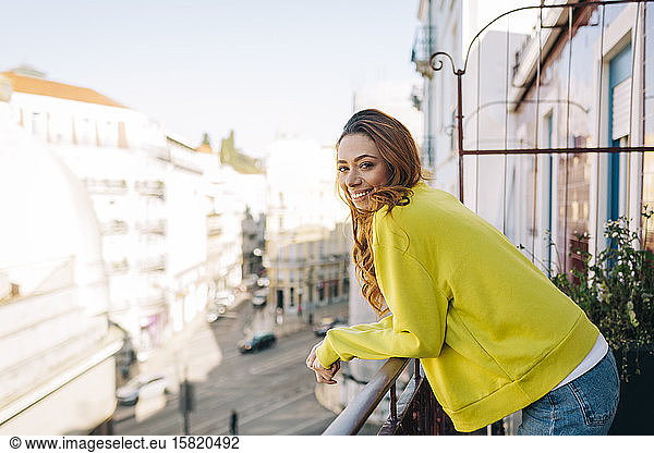 Portrait of happy young woman standing on balcony