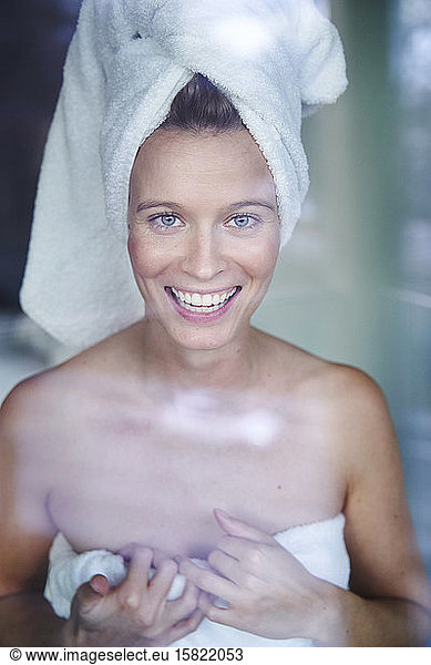 Portrait of happy young woman with her head wrapped in a towel