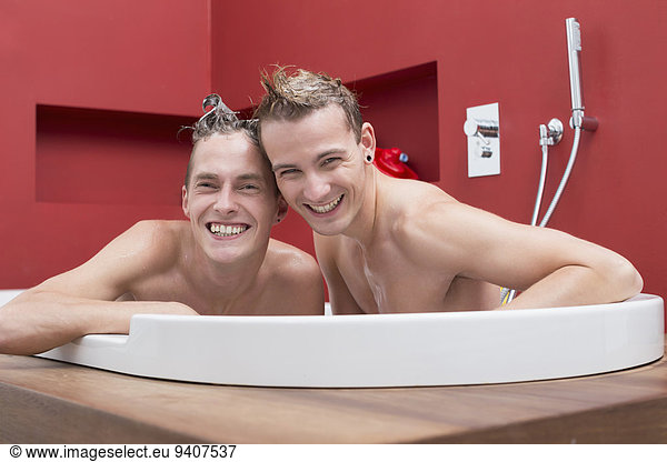Portrait of homosexual couple in bathtub,  smiling
