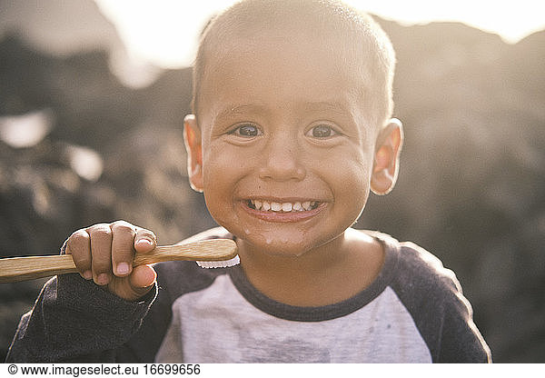 Portrait of kid brushing teeth with bamboo toothbrush