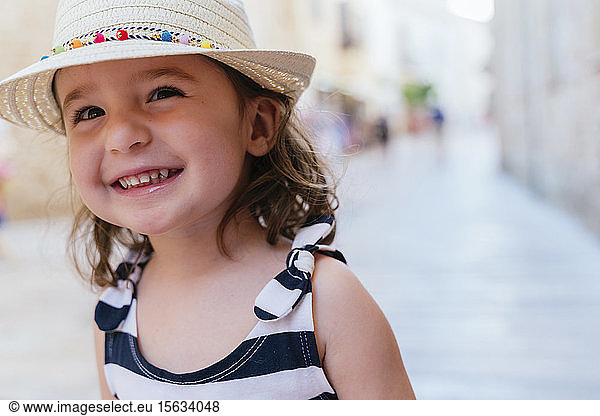 Portrait of laughing little girl wearing straw hat