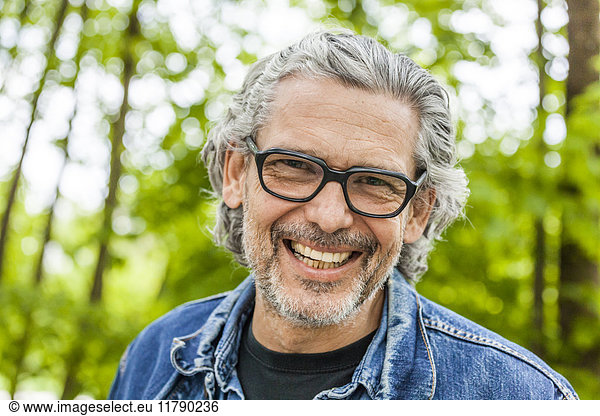 Portrait of laughing man with grey hair and beard wearing glasses