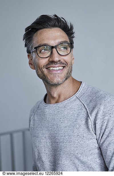 Portrait of laughing man with stubble wearing grey sweatshirt and glasses