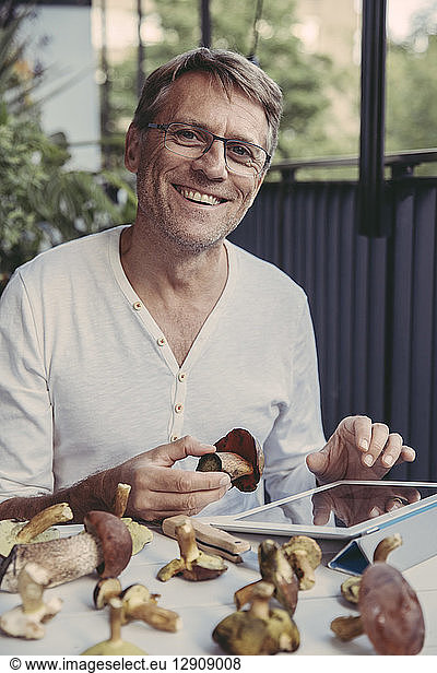 Portrait of laughing man with tablet holding scarletina bolete