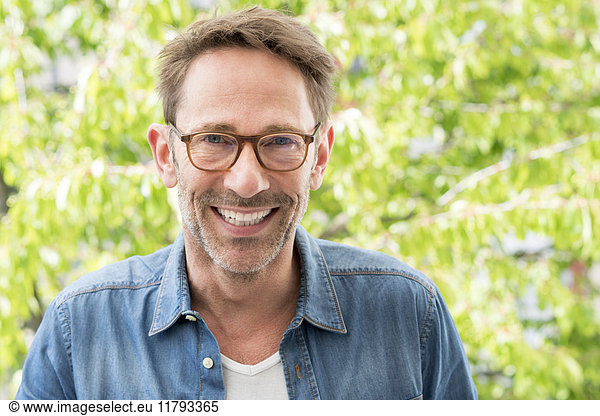Portrait of laughing mature man with stubble wearing glasses