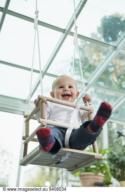 Portrait of laughing toddler sitting in a swing