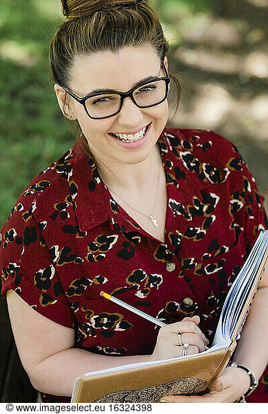 Portrait of laughing woman writing in notebook