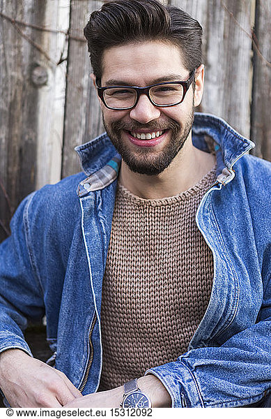 Portrait of laughing young man wearing glasses and denim jacket