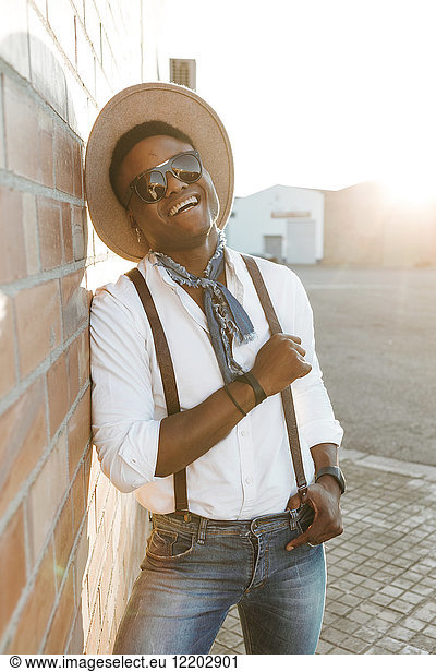 Portrait of laughing young man wearing hat and sunglasses