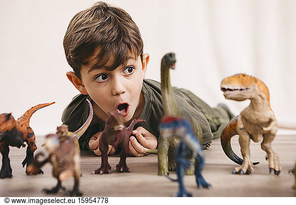 Portrait of little boy playing with toy dinosaurs