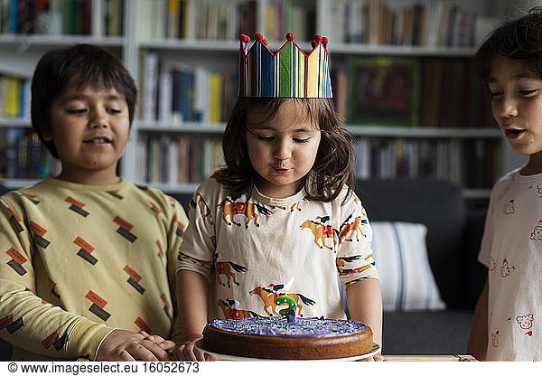 Portrait of little girl celebrating birthday with her older brothers at home