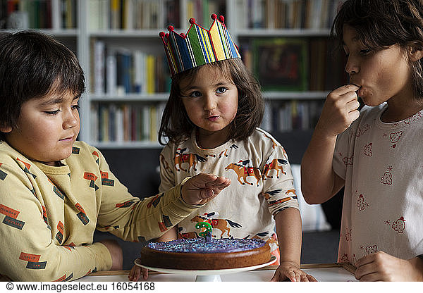 Portrait of little girl celebrating birthday with her older brothers at home
