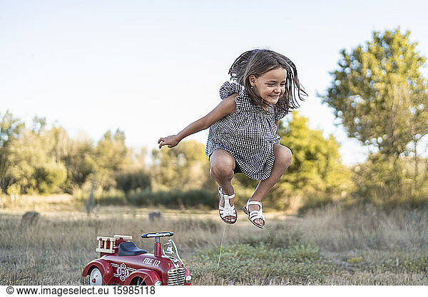Portrait of little girl jumping in the air in nature