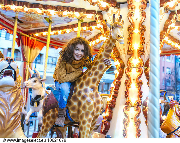 Portrait of little girl sitting on giraffe of a carousel