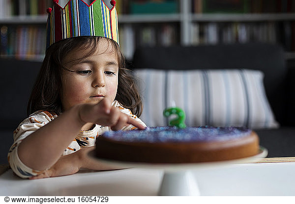 Portrait of little girl touching birthday cake