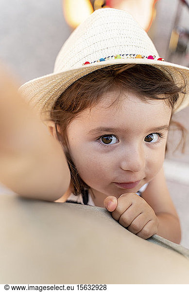 Portrait of little girl with brown hair and eyes wearing straw hat
