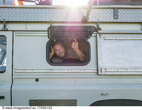 Portrait of male hiker looking at camera through window of off-road vehicle