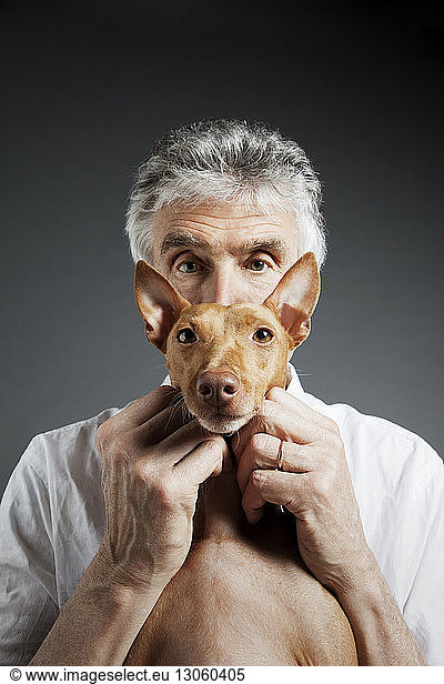 Portrait of man and dog against gray background
