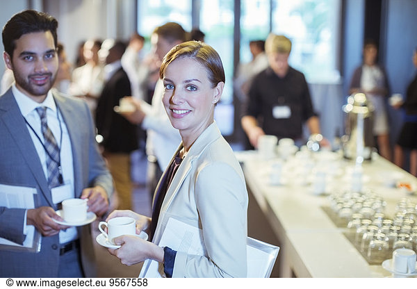 Portrait of man and woman standing in lobby of conference center during coffee break