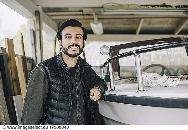 Portrait of man by nautical vessel in garage