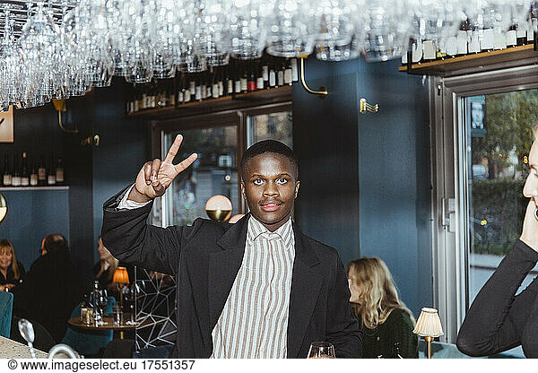 Portrait of man doing peace sign in bar