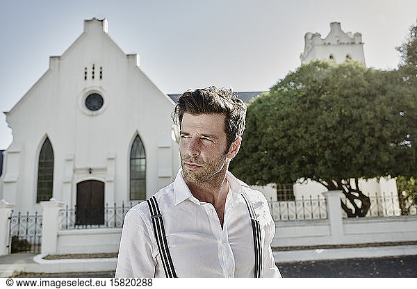 Portrait of man in old-fashioned clothes at a church in the countryside