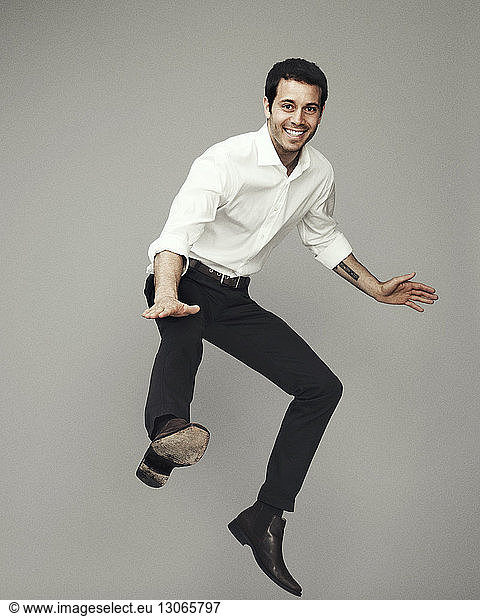 Portrait of man jumping against gray background