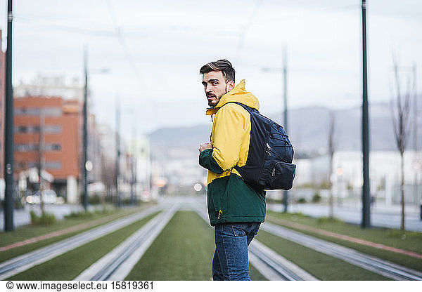 Portrait of man with backpack in the city on tram tracks