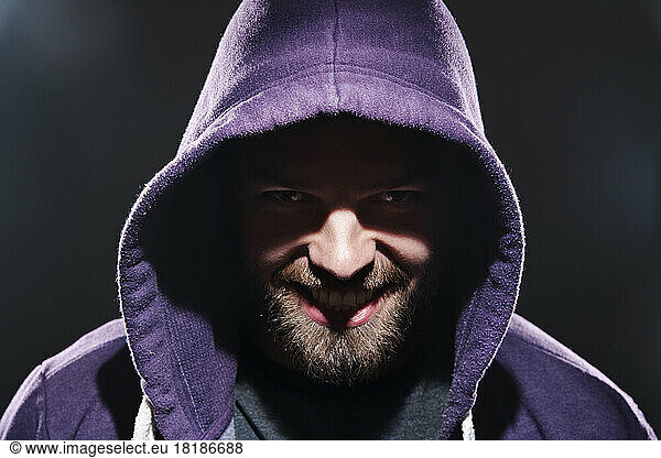 Portrait of man with hooded jacket in front of black background
