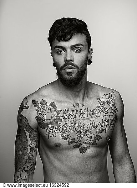 Portrait of man with tatoos on chest and upper arm