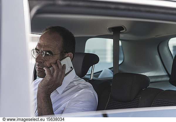 Portrait of mature businessman on the phone in car
