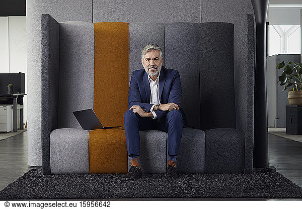 Portrait of mature businessman sitting on couch in office