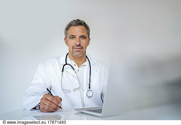 Portrait of mature doctor sitting at desk in medical practice