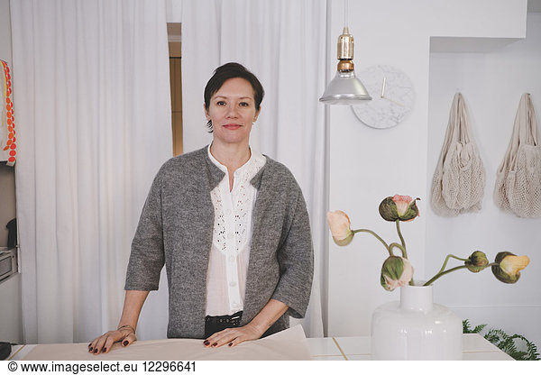 Portrait of mature female designer standing at desk in workshop