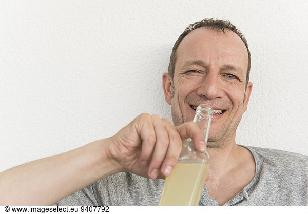 Portrait of mature man drinking drink from bottle  smiling