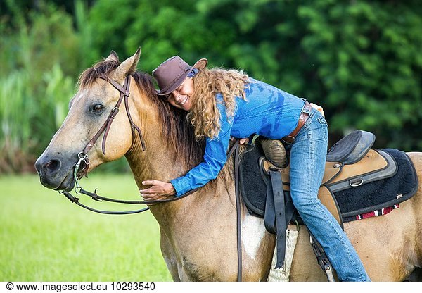 Portrait of mature woman  on horseback  hugging horse