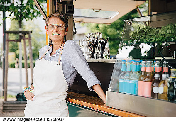 Portrait of mature woman standing by commercial land vehicle