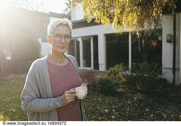 Portrait of mature woman with cup of coffee in garden