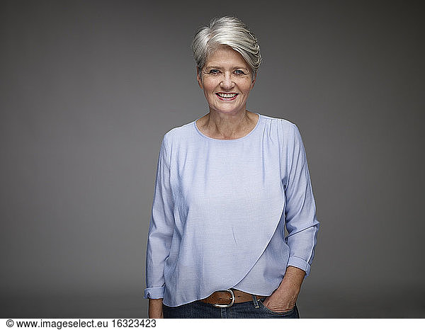 Portrait of mature woman with grey hair in front of grey background