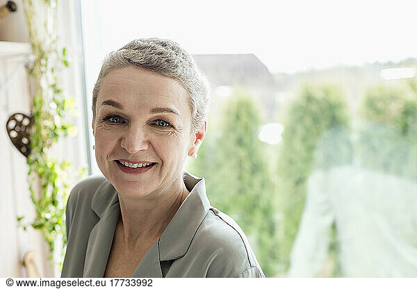 Portrait of mature woman with short grey hair at the window