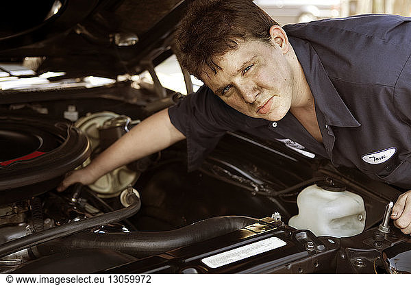 Portrait of mechanic repairing car engine