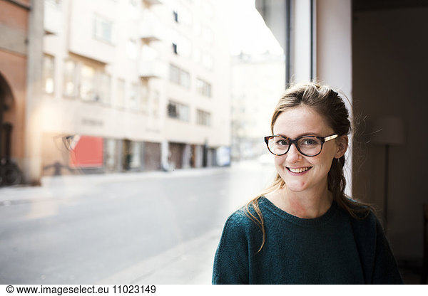 Portrait of mid adult businesswoman smiling by office window