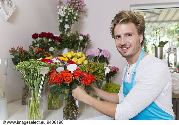 Portrait of mid adult man arranging flowers in vase  smiling