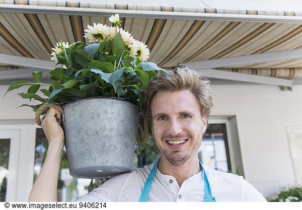 Portrait of mid adult man holding potted plant of flower  smiling