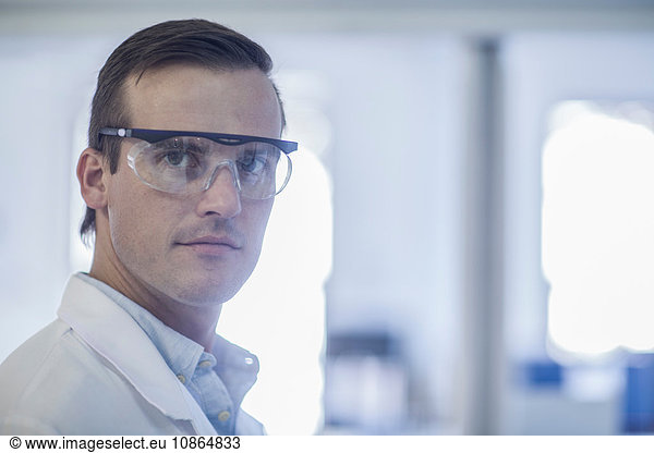 Portrait of mid adult man in laboratory  wearing safety goggles